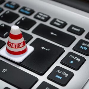 Miniature caution cone on a computer keyboard symbolizing data security and control.