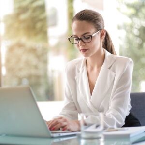 Confident businesswoman using a laptop at her desk, focused on her work.