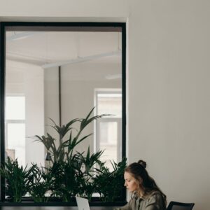 Woman working on a laptop in a minimalist home office with plants.