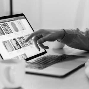 Black and white photo of a person shopping online on a laptop, highlighting e-commerce technology.